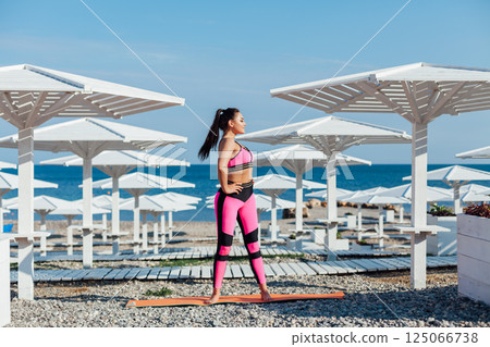 Brunette in sports gymnastics yoga asana on the beach by the sea 125066738