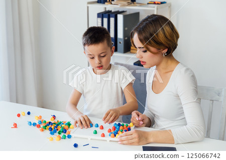 Female playing educational games with boy at table in classroom 125066742