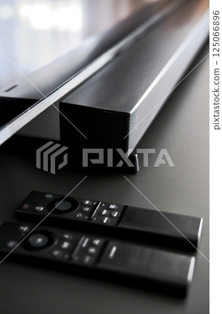 Modern soundbar and two sleek black remote controls 125066896