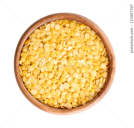 Yellow lentils in a wooden bowl. Dried seeds of a variety of Lens esculenta, a legume of small, round, and yellow in color fruits. High in protein and fiber, with soft and creamy texture, when cooked. 125067397