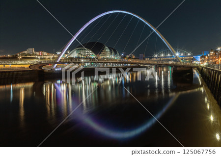 Night view of The Iconic gateshead millennium bridge spanning the River Tyne with Sage Gateshead with Tyne Bridge in the background. 125067756