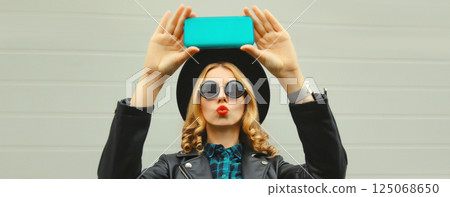 Stylish happy smiling young woman taking selfie with phone, beautiful girl using smartphone Stylish happy smiling young woman taking selfie with phone, beautiful girl using smartphone 125068650