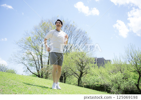 一名男子在清新的綠色天空下奔跑或慢跑的全身。令人耳目一新的鍛鍊和運動的形象。 一名男子在清新的綠色天空下奔跑或慢跑的全身。令人耳目一新的鍛鍊和運動的形象。 125069198