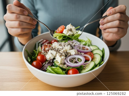 Fresh and healthy salad preparation with vegetables and cheese for a nutritious meal 125069282