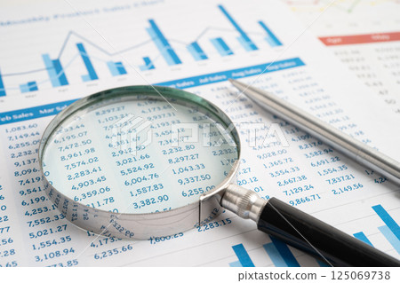 Magnifying glass on spreadsheet and graph paper. Financial data economy, Business. 125069738
