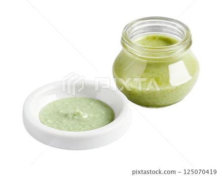 Wasabi Sauce A spicy wasabi sauce in a clear glass jar, its pale green color evident. A small glass dish 125070419