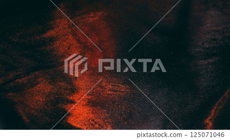 Shiny glitter. Sparkling fluid. Defocused orange bronze color ink in water chemical particles drop floating on art dark black abstraction. 125071046