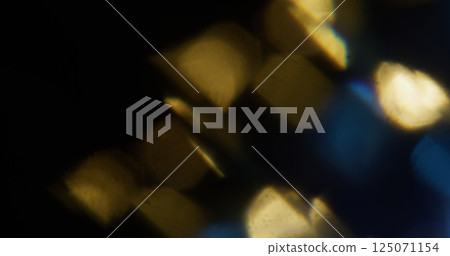 Reflection bokeh. Blur glint. Defocused blue yellow multicolor rainbow spectrum lens light flare on dark black art background. Reflection bokeh. Blur glint. Defocused blue yellow multicolor rainbow spectrum lens light flare on dark black art background. 125071154