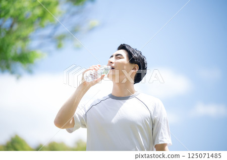 藍天下跑步或運動時補充水分(飲用水)的年輕男子的特寫鏡頭 藍天下跑步或運動時補充水分(飲用水)的年輕男子的特寫鏡頭 125071485