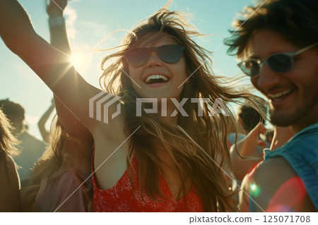 Young woman is dancing with her friends at a music festival, enjoying the music and the summer sun 125071708