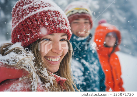 Three friends wearing winter clothes, smiling and having fun while it's snowing in a forest Three friends wearing winter clothes, smiling and having fun while it's snowing in a forest 125071720