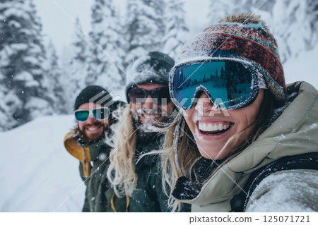 Three friends, covered in snow, are smiling while taking a selfie in a snowy forest Three friends, covered in snow, are smiling while taking a selfie in a snowy forest 125071721