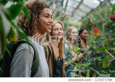 Group of four biologists is walking in a greenhouse, smiling and looking at plants 125071766