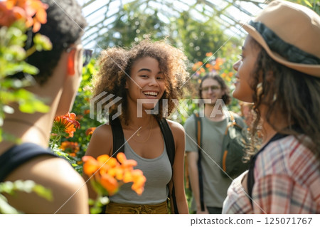 Four happy young people enjoying a sunny day out at a botanical garden, talking and laughing together 125071767