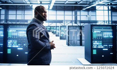 African american technician walking in data center, monitoring systems to identify errors. Man in server hub location doing diagnosis, looking for infrastructure bugs in need of repairing, camera B African american technician walking in data center, monitoring systems to identify errors. Man in server hub location doing diagnosis, looking for infrastructure bugs in need of repairing, camera B 125072024
