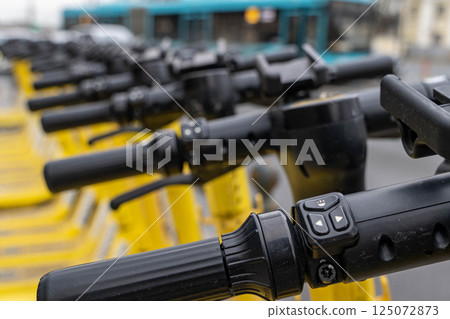 Row of yellow electric scooters ready for rent showing control panel and grips Row of yellow electric scooters ready for rent showing control panel and grips 125072873