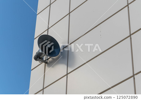 Loudspeaker announcing on white building with blue sky background Loudspeaker announcing on white building with blue sky background 125072890