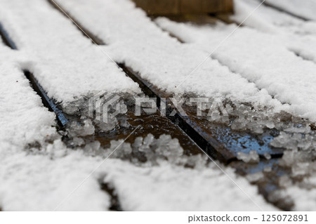 Melting snow on wooden deck creates icy surface in winter 125072891