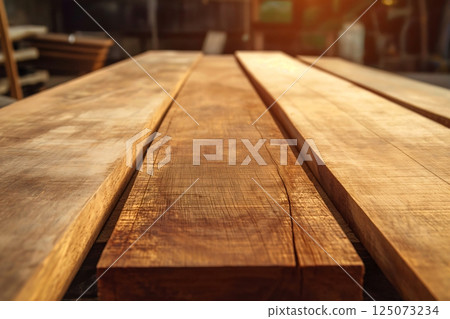 Warm sunlight highlights the beauty of wooden planks in a cozy carpentry workshop, showcasing craftsmanship for interior design, renovation, or diy projects 125073234