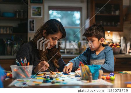 Mother and her young son are enjoying their time together, painting and making crafts at the kitchen table 125073729