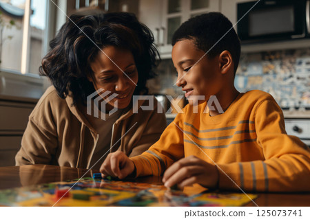 Mother and her son are playing a board game together in their kitchen, having fun and spending quality time Mother and her son are playing a board game together in their kitchen, having fun and spending quality time 125073741