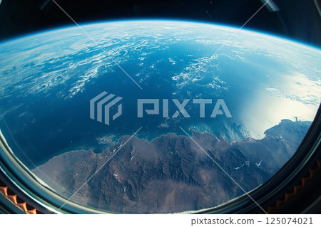 Spacecraft window is showing a view of earth with a beautiful blue ocean and coastline 125074021