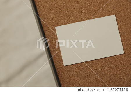 Blank business card, invitation mockup on brown cork texture tray. Blurred wrinkled beige cloth. Elegant branding template. Flat lay, top view, no people. Copy space. Modern stationery still life. 125075138