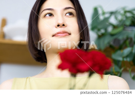 A young housewife wearing an apron holding a carnation 125076484