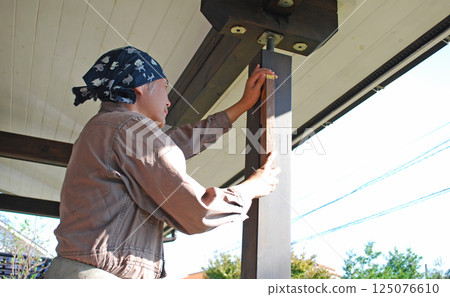 Carpentry: Man using a spirit level on a log house Carpentry: Man using a spirit level on a log house 125076610