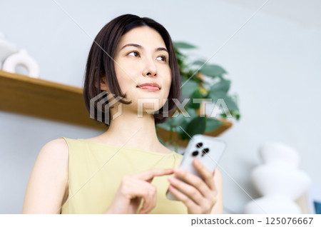 一位年輕女子在房間裡看著她的智慧型手機 125076667
