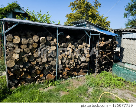 Neatly stacked pile of firewood under a canopy. Preparing for autumn or winter 125077739