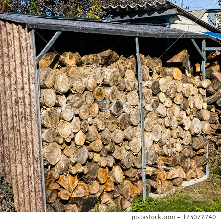 Neatly stacked pile of firewood under canopy. Preparing for autumn or winter 125077740