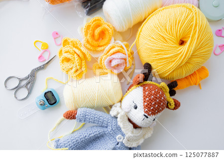 Crafting essentials. Yarn balls, crochet tools, and handmade toy 125077887