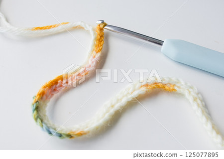 Colorful crochet chain with hook on white background 125077895