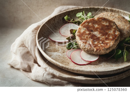 Macro close-up of plant-based protein patties garnished with radish on a ceramic plate Macro close-up of plant-based protein patties garnished with radish on a ceramic plate 125078360