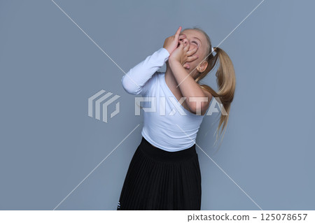 little girl shows off her bold and joyful personality with a playful pose, making the most of the studio setting. Her trendy one-shoulder top and pleated skirt add a stylish flair to the energetic 125078657