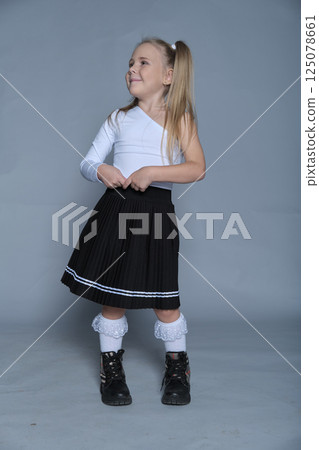 A confident young girl models a trendy black skirt and white top, perfect for children s fashion portfolios. 125078661