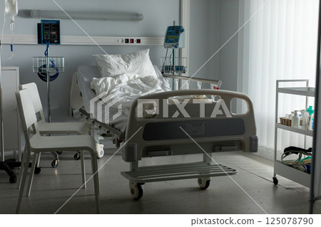 An empty hospital room featuring a bed along with various essential medical equipment and supplies An empty hospital room featuring a bed along with various essential medical equipment and supplies 125078790