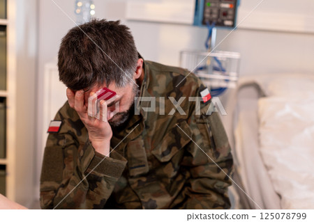 A soldier in distress suffering from an injury while receiving care in a medical setting 125078799