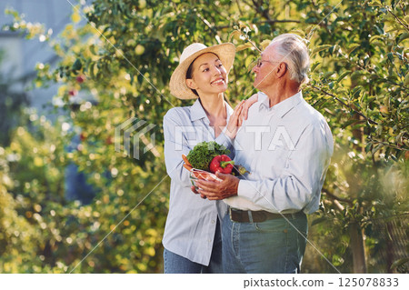 Smiling and holding vegetables. Daughter is with her senior father in the garden at daytime Smiling and holding vegetables. Daughter is with her senior father in the garden at daytime 125078833