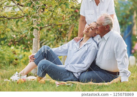 Sitting on the ground. Daughter is with her senior mother and father is in the garden 125078869