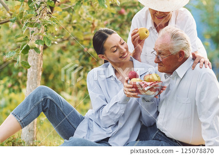 Sitting on the ground. Daughter is with her senior mother and father is in the garden 125078870