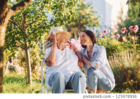 Sitting together. Young woman is with her senior mother is in the garden Sitting together. Young woman is with her senior mother is in the garden 125078936