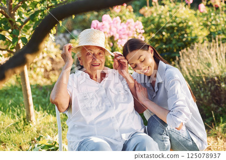 Sitting together. Young woman is with her senior mother is in the garden Sitting together. Young woman is with her senior mother is in the garden 125078937