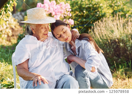 Sitting together. Young woman is with her senior mother is in the garden Sitting together. Young woman is with her senior mother is in the garden 125078938