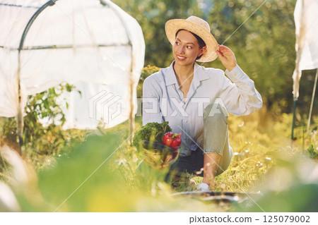 Sitting on the ground. Young cheerful woman is in the garden at daytime 125079002