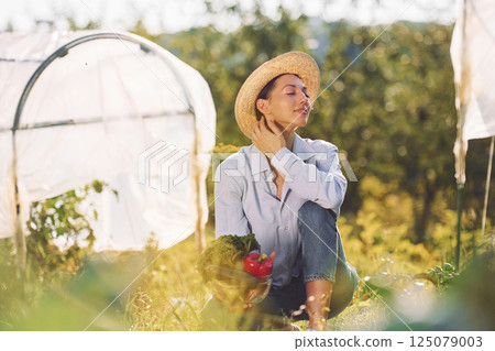 Sitting on the ground. Young cheerful woman is in the garden at daytime 125079003