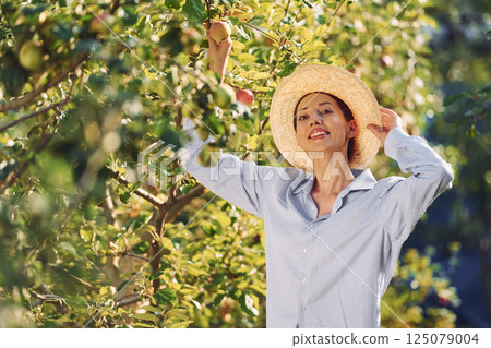 Standing and posing. Young cheerful woman is in the garden at daytime 125079004