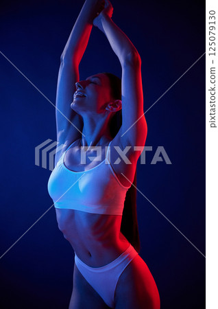 Beautiful colors. Young woman in underwear is in the studio with neon lights 125079130
