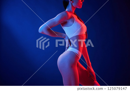 Blue and red colors. Young woman in underwear is in the studio with neon lights Blue and red colors. Young woman in underwear is in the studio with neon lights 125079147